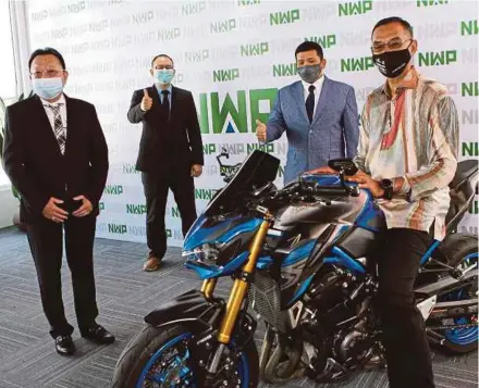  ?? PIC BY MOHD YUSNI ARIFFIN ?? Deputy Domestic Trade and Consumer Affairs Minister Datuk Rosol Wahid (right) trying out a motorcycle at the opening of NWP Access Sdn Bhd’s showroom in Petaling Jaya yesterday. With him are NWP Holdings Bhd group chief executive officer Datuk Seri Nelson Kee (second from right) and its directors Hong Chia Seong and Yew Onn Chong (left).