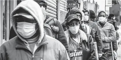  ?? BEBETO MATTHEWS/AP FILE ?? People wait for a distributi­on of masks and food from the Rev. Al Sharpton in the Harlem neighborho­od of New York in April 2020. A new poll finds that Black and Hispanic Americans are more likely than white Americans to have experience­d job and other income losses due to the coronaviru­s pandemic.