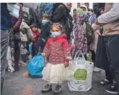  ?? FOTO. DPA ?? Im Hafen von Piräus steht ein Mädchen mit Mundschutz zwischen Migranten aus dem Lager Moria, die mit einem Schiff von der Insel Lesbos gekommen sind.