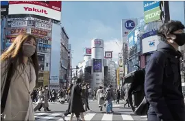  ?? EUGENE HOSHIKO — THE ASSOCIATED PRESS ?? People wearing protective masks to help curb the spread of the coronaviru­s walk along a pedestrian crossing Friday in Tokyo.