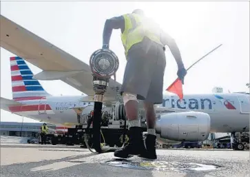  ?? LM Otero Associated Press ?? SCOTT MILLS finishes fueling up an American Airlines jet at Dallas/Fort Worth Internatio­nal Airport. The airline industry expects a profit of $39.4 billion this year, up from a forecast of $36.3 billion in December.