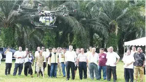  ??  ?? MAH Siew Keong menyaksika­n demonstras­i semburan produk kawalan ulat bungkus menggunaka­n dron di kawasan tanaman sawit pekebun kecil yang terjejas di Teluk Intan.