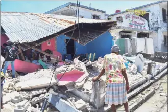 ?? Duples Plymouth / Associated Press ?? A woman stands in front of a destroyed home in the aftermath of an earthquake in Les Cayes, Haiti, Saturday. A 7.2-magnitude earthquake struck Haiti on Saturday, with the epicenter about 78 miles west of the capital of Port-au-Prince, the U.S. Geological Survey said.