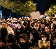  ?? Photo: Reuters ?? People in Beijing last Sunday hold white sheets of paper as a form of protest against rigid coronaviru­s restrictio­ns.