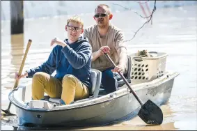  ?? AP/CHRIS MACHIAN/Omaha World-Herald ?? Treyton Gubser (left) and his uncle Daniel Gubser paddle using shovels Wednesday through floodwater in Hamburg, Iowa, after rescuing the family cat, Bob, seen riding in the laundry basket.
