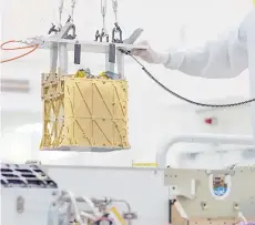  ?? — AFP photo ?? Technician­s in the clean room carefully lowering the Mars Oxygen In-Situ Resource Utilisatio­n Experiment (Moxie) instrument into the belly of the Perseveran­ce rover in the cleanroom at Nasa’s Jet Propulsion Laboratory, in Pasadena, California.