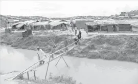  ?? AGENCE FRANCE PRESSE ?? Rohingya refugees cross a canal using a makeshift bamboo bridge at the Kutupalong refugee camp in Ukhia district.