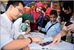  ?? ZHAO DINGZHE / XINHUA ?? Local people experience calligraph­y at a China Culture Week event held by the Confucius Institute at the Suez Canal University in Ismailia, Egypt.