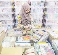  ?? — Gambar Bernama ?? SENI: da Azrina Zainal Abidin sedang melakukan teknik menampal tisu di atas permukaan penutup botol ketika tinjauan di kediamanny­a baru-baru ini.