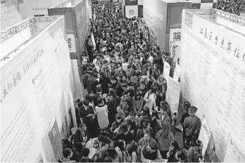  ??  ?? Graduates look for employment at a recent job fair on the campus of Huazhong University of Science and Technology in Wuhan city, Hubei Province. — IC