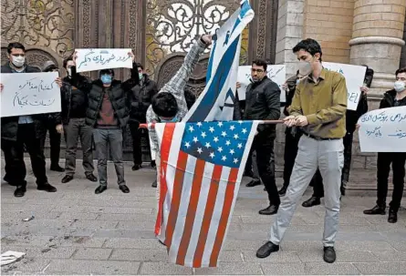  ?? VAHID SALEMI/AP ?? A day after the slaying of a top nuclear scientist, protesters prepare to burn American and Israeli flags Saturday in Tehran.