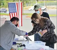  ?? Dan Watson/The Signal ?? (Above) Voters check in at the Castaic Regional Sports Complex on Tuesday. The 25th Congressio­nal district special election will decide who fills the U.S. House seat left vacant after former Rep. Katie Hill stepped down last year. (Below) Voting center lead Kevin Myvett hands an “I Voted” sticker to a resident who brought his ballot to the drop-off box at College of the Canyons in Valencia. (Left) Voting clerk Alan Ramero sanitizes the kiosk in the voting booths at the sports complex Tuesday.