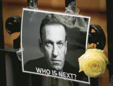  ?? KIRSTY WIGGLESWOR­TH/AP ?? A flower and a picture are left as a tribute to Russian politician Alexei Navalny near the Russian Embassy in London on Feb. 18.