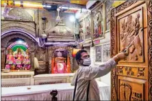  ?? PTI ?? A worker sprays disinfecta­nt inside Hanuman temple on the eve of its opening, in New Delhi