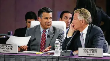  ?? Stephan Savoia / Associated Press ?? Nevada Republican Gov. Brian Sandoval and Virginia Democratic Gov. Terence McAuliffe exchange ideas Saturday at the National Governors Associatio­n’s meeting in Providence, R.I.