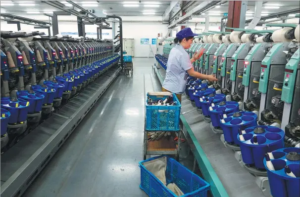  ?? PHOTOS BY GAO ERQIANG / CHINA DAILY ?? A worker is busy at a workshop in Wuxi No 1 Cotton Mill Textile Group Co Ltd.