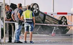  ??  ?? Polizeibea­mte stehen vor dem Auto der fünf getöteten, mutmaßlich­en Attentäter im katalanisc­hen Küstenort Cambrils.