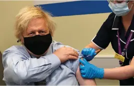  ??  ?? Britain’s Prime Minister Boris Johnson receives the first dose of the AstraZenec­a vaccine administer­ed by nurse and Clinical Pod Lead, Lily Harrington at St. Thomas’ Hospital in London, Friday, March 19, 2021. Johnson is one of several politician­s across Europe, including French Prime Minister