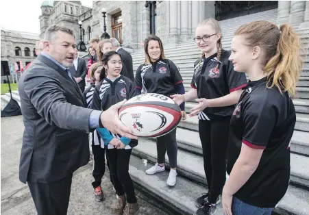  ?? DARREN STONE, TIMES COLONIST ?? Rugby Canada’s Gareth Rees presents Shoreline Community Middle School rugby players with a national team ball at the legislatur­e on Tuesday during a funding announceme­nt for the women’s sevens tournament in Langford.