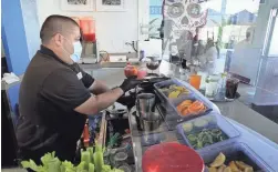  ?? DAMIAN DOVARGANES/AP ?? Barman Gustavo prepares drinks behind protective plexiglass on Wednesday at Maria Sol on the Santa Monica Pier in California.