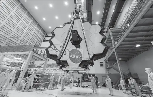  ??  ?? Technician­s lift the mirror of the James Webb Space Telescope using a crane at the Goddard Space Flight Center. The telescope’s 18-segmented gold mirror is specially designed to capture infrared light from the first galaxies that formed in the early universe. — All photos by IC