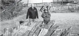  ?? STEVE PFOST Newsday via AP ?? Tony Femminella, executive director of the Fire Island Lighthouse Preservati­on Society, and Betsy DeMaria, museum technician with Fire Island National Seashore, stand beside a section of the hull of a ship believed to be the SS Savannah, at the Fire Island lighthouse in January. The SS Savannah wrecked in 1821 off Fire Island.