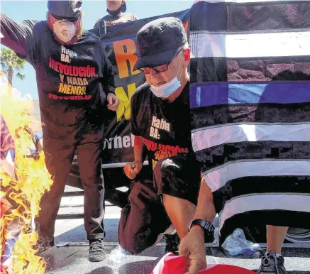  ?? PHOTO: REUTERS ?? Defiant: Gregory Johnson (right), whose burning of an American flag in 1984 led to a Supreme Court ruling upholding the act as free speech, sets fire to one in LA.