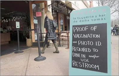  ?? JANE TYSKA — BAY AREA NEWS GROUP ?? Sarah Bishop of Berkeley walks by a sign requiring proof of vaccinatio­n outside the Tacubaya restaurant recently on Fourth Street in Berkeley.