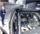  ?? NG HAN GUAN/AP ?? A man stands by as two people check out the all-electric Volvo XC40 in April in Shanghai, China. Volvo is planning to offer only electric vehicles by 2030.