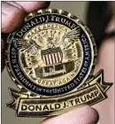  ??  ?? The presidenti­al seal has been replaced by an eagle, left, bearing President Donald Trump’s signature. Both sides feature Trump’s slogan, “Make America Great Again.”