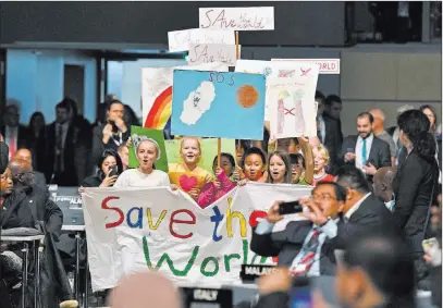  ?? Martin Meissner ?? The Associated Press Children with banners reading “Save the world” march between delegates during the opening Monday of the COP 23 Fiji U.N. Climate Change Conference in Bonn, Germany.