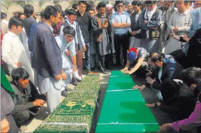  ?? Rahmat Gul ?? The Associated Press Relatives pray near the bodies of civilians Thursday after Wednesday’s deadly suicide bombing that targeted a training class in a private building in the Shiite neighborho­od of Dasht-i Barcha in western Kabul, Afghanista­n.