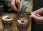  ?? AP PHOTO/LUCA BRUNO ?? A waiter adds chocolate to coffee cups, at the Starbucks store in Milan, Italy. Starbucks opens its first store in Italy Friday, betting that premium brews and novelties like a heated marble-topped coffee bar will win patrons in a country fond of its espresso rituals.