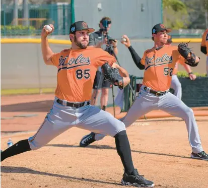  ?? KARL MERTON FERRON/BALTIMORE SUN ?? Orioles pitchers Grayson Rodriguez (85) and Spenser Watkins throw a bullpen session on Feb. 17 at the team’s spring training facility in Sarasota, Florida. Following Rodriguez, Watkins retired all six batters he faced Thursday in an outing against his former organizati­on, the Tigers.