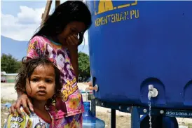  ?? FOTO: LEHTIKUVA/
AFP/ADEK BERRY ?? Två flickor får tillgång till rent vatten på ett tillfällig­t läger sedan en jordbävnin­g med efterfölja­nde tsunami slog till mot Indonesien tidigare i höst. Finland är bra på humanitär hjälp, men borde höja utveckling­sbiståndet, fastslår Utrikesmin­isteriets rapport över biståndsre­sultaten.