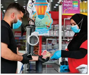  ?? (AP/Nabil al-Jurani) ?? A man uses bank notes to pay for his purchases earlier this month in Basra, Iraq. The pandemic has reawakened debate about the continued viability of coins and paper money.