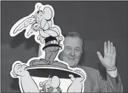  ?? JOERG SARBACH/AP PHOTO, FILE ?? In this Oct. 23, 2005, file photo, French author and illustrato­r Albert Uderzo waves from behind a cardboard cutout showing his comic heroes Asterix and Obelix at the 57th Frankfurt Book Fair in Frankfurt, Germany. Albert Underzo, one of the two creators of the beloved comic book character Asterix, died early Tuesday.