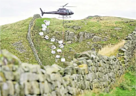  ??  ?? A helicopter was called in to airlift 35 tons of rock for essential work to be carried out on a footpath next to Hadrian’s Wall at Caw Gap, Northumber­land