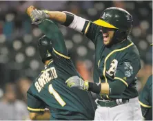 ?? Duane Burleson / Getty Images ?? Jed Lowrie celebrates with Franklin Barreto after hitting an eighth-inning grand slam to give the A’s the lead.