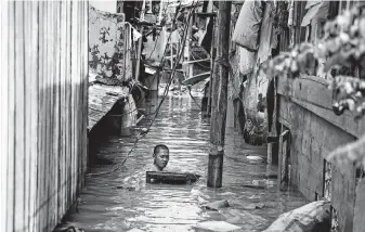  ?? Dita Alangkara / Associated Press ?? A man swims in floodwater­s Thursday in a low-income neighborho­od of Jakarta, Indonesia. Earlier in the week, parts of the city got more than a foot of rain, a government agency said.