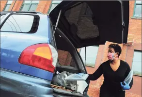  ?? Christian Abraham / Hearst Connecticu­t Media ?? Principal Collette Fearon puts a laptop into the truck of a vehicle of an awaiting family during a laptop giveaway at New Beginnings Family Academy in Bridgeport on May 1. Local charter schools were shut out of the school district's free computer distributi­on, but New Beginnings donors stepped up, letting the school provide several hundred laptops to its students.