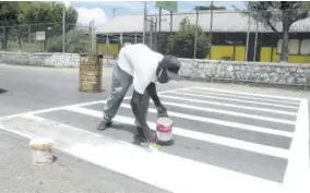  ?? ?? A man paints a pedestrian crossing in front of Tulloch Primary School in this Labour Day 2018 file photo. This year Jamaicans have been encouraged to labour at home because of the pandemic.