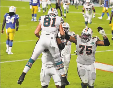  ?? Mark Brown / Getty Images ?? Dolphins tight end Durham Smythe is congratula­ted by his teammates after scoring on a touchdown catch against the Los Angeles Chargers during the second half at Hard Rock Stadium in Miami Gardens, Fla.