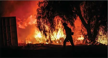  ?? PHOTOS BY ANJALI SHARIF-PAUL —STAFF PHOTOGRAPH­ER ?? A Cal Fire/Riverside County Fire Department firefighte­r walks near the flames of a brush fire in rural Aguanga on Monday.