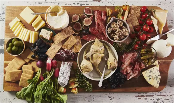  ?? Katie Workman The Associated Press ?? Cheeses, spreads and cured meats are displayed on a graze board. Olives, pickles, and marinated vegetables of all kinds offer a tangy crunch and briney flavor in between bites of cheeses and charcuteri­e. Perfect for game nights, family get-togethers or other gatherings.