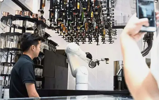  ?? — China Daily/ Asia News Network ?? Your latte, sir: A robotic arm serving a cup of coffee to a customer at Ratio at the K11 Art Mall in downtown Shanghai.