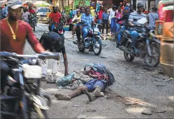  ?? Ramon Espinosa Associated Press ?? A BODY LIES in the middle of the street as commuters make their way through Port-au-Prince, Haiti’s capital. Unrelentin­g violence has killed or injured more than 2,500 people in the country from January to March.