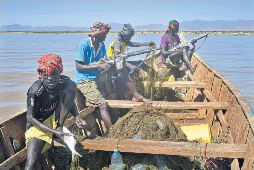  ??  ?? TOOLS OF THE TRADE: Armed fishermen from Kenya’s Turkana county return from a fishing expedition aboard a boat near Lowarengak, northern Kenya.