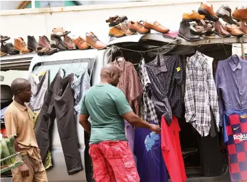  ??  ?? A customer selects clothes from a vendor selling his wares from a car in Harare yesterday.
Picture: John Manzongo