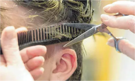  ?? FOTO: SEBASTIAN KAHNERT/DPA ?? Hannover: Eine Friseurin schneidet die Haare einer Kundin. Wirtschaft­sverbände fordern angesichts des wochenlang­enLockdown­s vehement einen Fahrplan zur Öffnung und warnen vor einer Pleitewell­e.